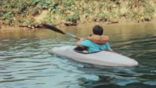 一个男孩在美丽的湖上划着皮划艇 用双桨桨在乡间平静的河流中熟练地航行 轻松而巧妙地把刀片拉入水中 — 图库视频影像