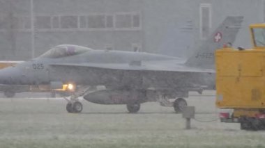 Military pilot in the cockpit of his supersonic fighter jet as it rolls during a heavy snowfall. Rare video to find. McDonnell Douglas F-18 Hornet of Swiss Air Force. Meiringen Air Base Switzerland in