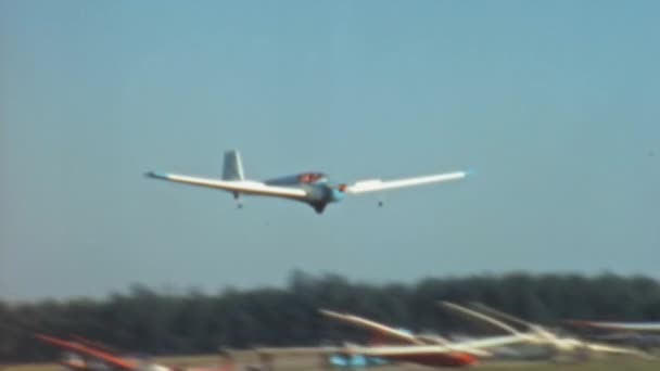 一台老式的机动滑翔机带着螺旋桨着陆 发动机停在草地跑道上 周围都是滑翔机和轻型飞机 Slingsby 61A Falke Venture Version Scheibe 25B — 图库视频影像