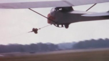 Tarihi planör, kanadı tutan bir asistanla vinçle kalkışa geçiyor. Slingsby T.21 açık kokpit, Kraliyet Hava Kuvvetleri Süzülme ve Yükselme Derneği RAFGSA 'nın iki koltuklu planörüyle yan yana.