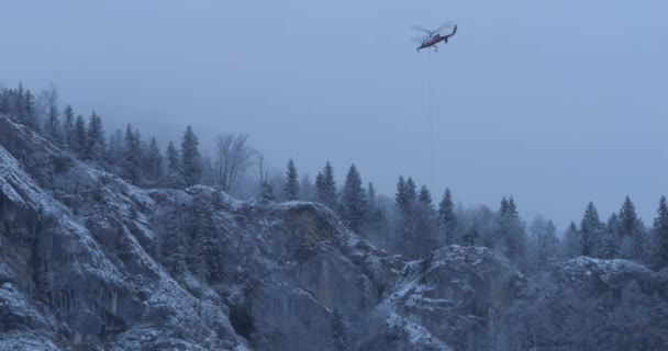 Изолированный Вертолет Стационарном Полете Возле Крутого Снежного Склона Лесистой Горы — стоковое видео