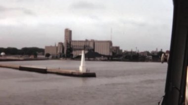 Scenic views from the Niagara River, New York cruise tour featuring a jetty, a large white monument and an office building across the river. Historical footage of the 1960s.