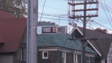 Sokak ismiyle sokak tabelası. Toronto Kanada 'daki Yonge Sokağı' nda el kamerasıyla 1970 'lerin tarihi görüntüleri çekildi. Arka planda düzinelerce güç kablosu olan pilon