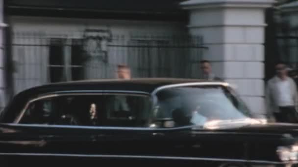 ワシントンDcのホワイトハウスの門から出てくるヴィンテージの黒い車 門の近くに立っている警備員や労働者が通り過ぎる 1960年の貴重なヴィンテージ映像 — ストック動画