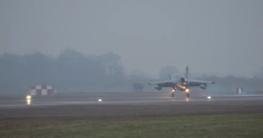 Küçük bombardıman uçağı sisin dışında belirir ve ışıklar açıkken ve fren yapmak için burnu yukarıda tutarken yansımalarla yere iner. AMX Ghibli hafif ses altı saldırı uçağı İtalyan savaş uçağı