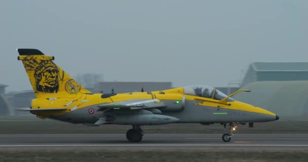 灰色の霧の日に滑走路にタクシー戦闘機 黄色の背景にアメリカインディアンの黒いシルエット コックピット サルテのパイロットだ Amxジブリ軽亜音速地上攻撃戦闘機 — ストック動画