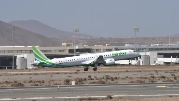 ガンド空港グラン カナリア諸島スペイン2021年10月21日 緑と白のリージョナル旅客機が晴れた日に離陸します サイドビュー Binter CanariasのEmbraer E195 — ストック動画