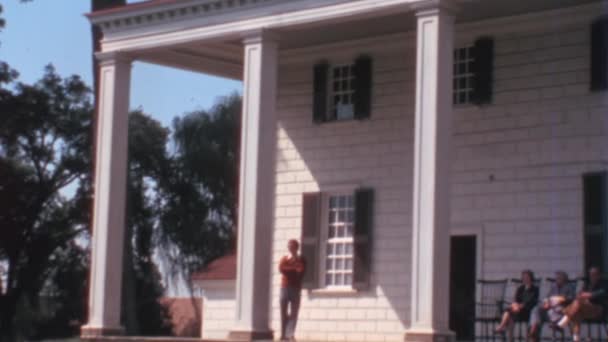 1970年代にマウントバーノンのジョージ ワシントン ハウス マンションのポルティコ 3人の女性観光客が座る晴れた日と白人男性が歩くと風景を見て — ストック動画