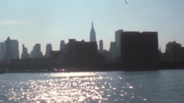移動船からバックライトのマンハッタンスカイラインの風景 ニューヨーク港の水に光の反射 1970年代スーパー8Mm映像復元 — ストック動画
