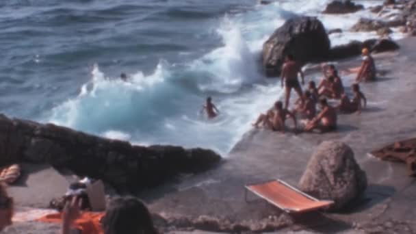 クロアチアのドゥブロヴニクのビーチでの楽しい時間は 1970年代に映画で捉えられました 波で遊ぶことで太陽とビーチを楽しむ人々のグループを見ることができますその魅力的でノスタルジックな — ストック動画
