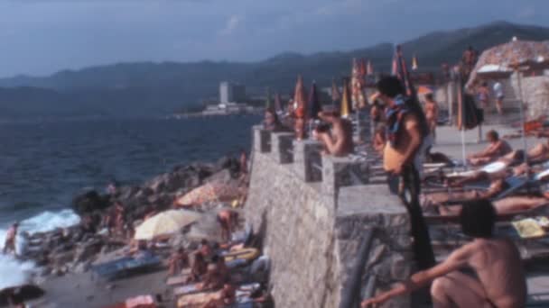 1970年の夏にドゥブロヴニクで開催されたこの魅力的な高角度ビデオは 人々と人生に満ちていた混雑したビーチにメモリレーンを歩いてください — ストック動画