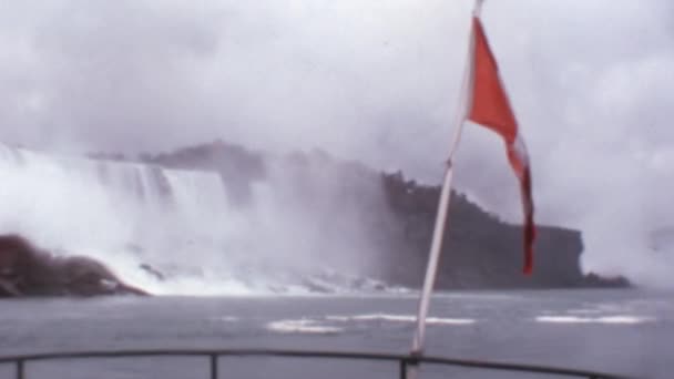 カナダ旗旗竿に手を振る ナイアガラの滝曇りの日の背景 1970年代の劇的なアーカイブ映像スーパーMmフィルムリールからデジタル化 — ストック動画