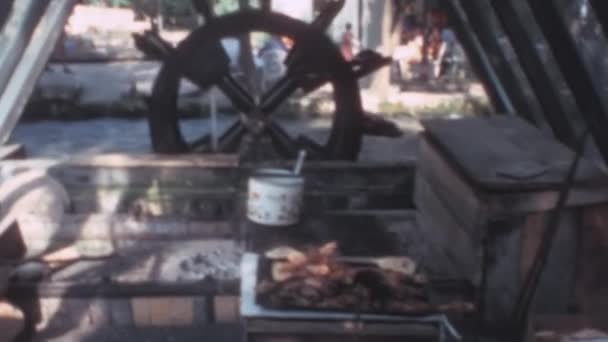 木製のミルのホイールは 小さなストリームの水でプッシュオンにします 肉はグリルで調理されます 1970年代の懐かしいビデオの中でリラックスしたシーン プリブスコ湖ジェゼロIn Jajce Bosnia Erzeovina — ストック動画
