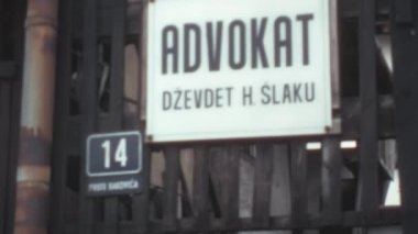 Bir binanın demir giriş kapısından sarkan beyaz arka planda siyahlı Advokat Cevdet Slaku yazan bir tabelayı kapat. Saraybosna 'daki Bakovica Caddesi Stari Grad. 1970 'ler Bosna