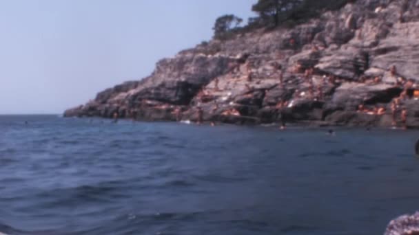 大约在1970年左右 一大群人在杜布罗夫尼克附近蓝色的亚得里亚海里泡着太阳和游泳 存档取自一艘船的老式手提式录像 — 图库视频影像