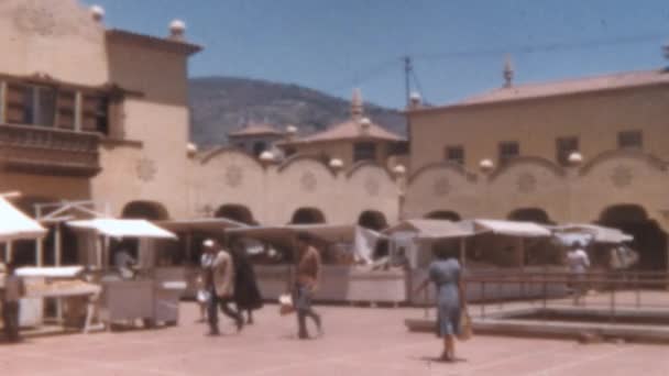 人々は露店の屋台で日当たりの良い広場を歩きます サンタ クルス テネリフェのヌエストラ セノーラ アフリカ市場 1950年代ヴィンテージ映像8Mmレトロスタイルで復元 — ストック動画