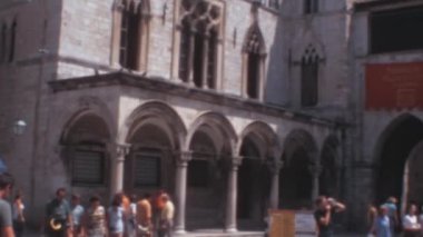 1970 'lerde Dubrovnik Şehir Merkezi Hırvatistan' daki Divona Sponza Sarayı 'nın ön cephesine yakın turistler. Ziyaretçiler, Ragusa kültürünün ve kültürünün özünü yansıtan karmaşık ayrıntıları karşısında büyülendiler.