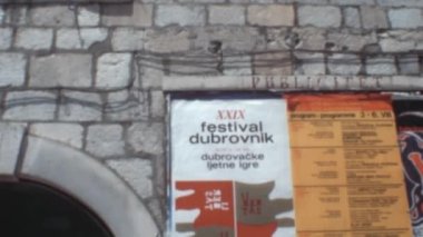 Dubrovnik Festivali 'nin renkli posteri kemerli girişin yanındaki eski bir tuğla duvara yapıştırıldı. Ünlü Avrupalı turistlerin Hırvatistan 'a 1970 yılında çekilen nostaljik görüntüleri.