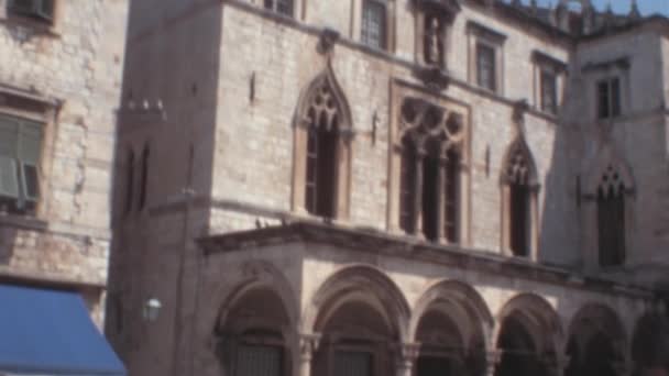 旧市街のディボナ スポンザ宮殿のファサード1970年代にクロアチアのドゥブロヴニク市内中心部 アーチ型の窓の複雑な詳細は ドゥブロヴニクの豊かな文化と歴史の本質を捉えています — ストック動画