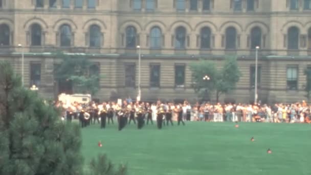 1970年代カナダのオタワにあるカナダ議会議事堂の隣に集まった群衆の前で演奏する儀式バンドのアーカイブ映像 — ストック動画