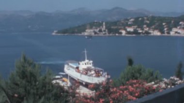 Hırvatistan 'ın çarpıcı Dalmaçya kıyıları boyunca denize demirlemiş olan yat, kayalık bir ada zemininin engebeli güzelliğiyle kucaklanıyor. Bu sahne 1970 'lerin ebedi kıyı cazibesini çağrıştırıyor. Jugoslavia 'da