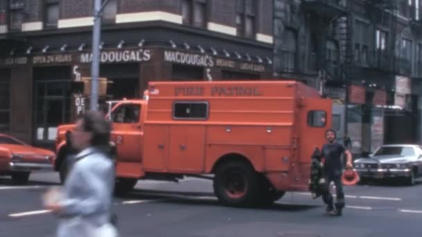 1970年代のヴィンテージ映像は ニューヨーク市の消防士がトラックから安全装備を奪い ヘルメットやベストを装着し 街頭を火に向かって走っている様子を示している — ストック動画