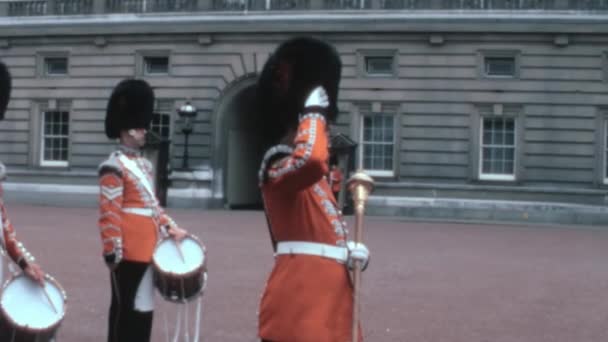 王立衛兵は 1970年代のヴィンテージビデオでイギリスのバッキンガム宮殿のガード変更式でイギリス王室ファミリーに給料を支払っている — ストック動画