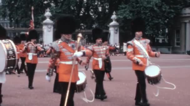 1970年代の伝統的な軍事儀式から見たこの歴史的な見解では コールドストリーム警備隊の軍隊は ロンドンのバッキンガム宮殿で愛国心を持って演奏しています — ストック動画