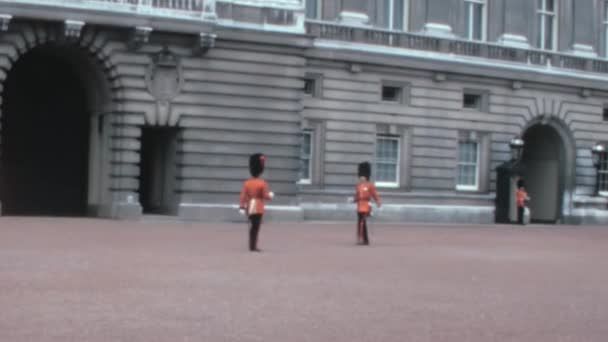 1970年代のパノラマビューでは イギリス衛兵がロンドンのバッキンガム宮殿の新しい王室警備隊に儀式的な鍵のセットを与えている — ストック動画
