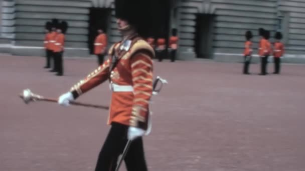 1970年代のヴィンテージ ビデオ コールドストリーム ガードは ロンドンのバッキンガム宮殿でイギリス王室が主催するガード変更式で公式の休憩を取った — ストック動画