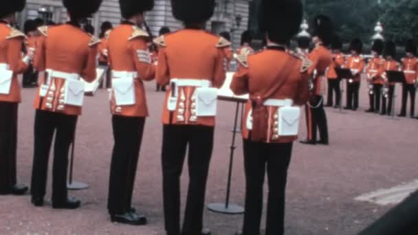 1970年代の歴史的なビデオは イギリスのバッキンガム宮殿で伝統的な軍事音楽を演奏するバンドをリードするコールドストリームガードのバンドマスターを示しています — ストック動画