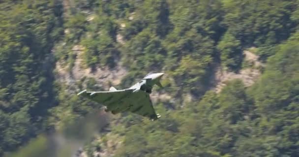 北约战斗机喷气式战斗机以全速前进的速度飞越阿尔卑斯山谷 可见余焰火焰 德国空军具有绿色木材和山脉背景的欧洲战斗机台风 — 图库视频影像
