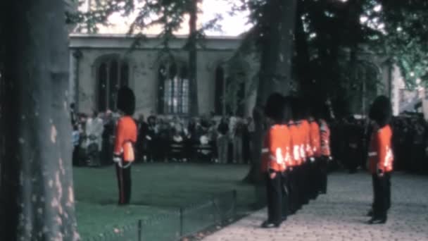 上世纪70年代 游客们在伦敦塔楼皇后区的花园中观看了一群完美排列的冷流卫兵的档案镜头 — 图库视频影像