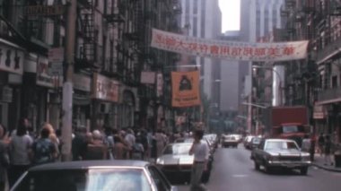 1970 'lerde New York' ta Çin Mahallesi 'nin hareketli ve hareketli sokakları. Amerikan arabaları ve restoranların ve dükkan ışıklarının önünden geçen insanları görüyor musun? Hepsi renkli mağazaların arka planına kurulmuş.