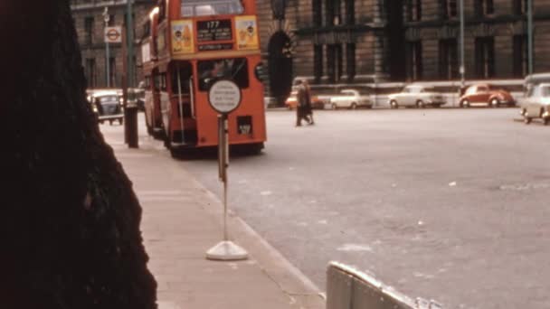 ダブルデッカーバスは 美しいクラシック建築に囲まれたシティダウンタウンの旅客ディスクの間に駐車しました 1970年代 ロンドン ヴィンテージ フッテージ — ストック動画
