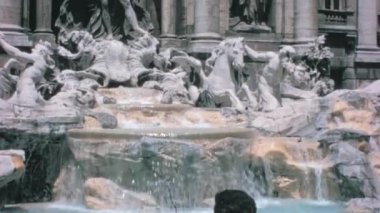 Ziyaretçiler Roma Şehir Merkezi 'ndeki Trevi Çeşmesinin Karmaşık Mimarisinin keyfini çıkarıyorlar. Mimari ve Doğal Elementlerin Uyumlu Karışımı Büyüleyici Bir Görüntü Yaratıyor. Dolce Vita 1960 'lar Roma Vintage
