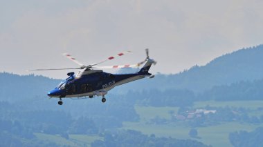 Mavi bir AW169 polis helikopteri Slovenya 'nın kırsal kesimlerinde devriye gezerken, kırsal manzarası da açık. Boşluğu kopyala.