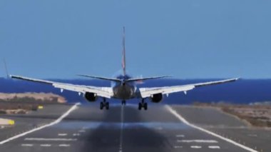 Gran Canaria, İspanya, 21 Ekim 2021 - Boeing 737 TUI Airways D-ATUO 'nun çarpıcı okyanus manzaralı ve arka planda tekneleri bulunan bir havaalanına iniş görüntüsü.