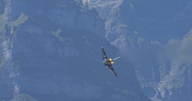 Mollis, İsviçre, 19 Ağustos 2023: Bir Alman Eurofighter Typhoon İsviçre zirveleri üzerinde alçaktan uçuyor, mükemmel bir kopya alanı ve doğayla çarpıcı bir tezat sağlıyor.