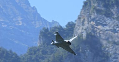 Mollis İsviçre 19 Ağustos 2023: Yeşil Alp Vadisi 'ndeki dağlara yakın bir uçuşta avcı uçağı. Alman Hava Kuvvetleri 'nden Eurofighter Typhoon. Boşluğu Kopyala.