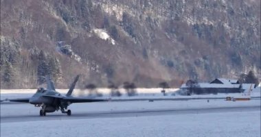 Meiringen, Switzerland, January 19, 2023: Fighter jet taxis on the runway, surrounded by a breathtaking, snow covered landscape. McDonnell Douglas F-18 Hornet of Swiss Air Force for WEF security. 