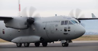 Cerklje Slovenya 20 Aralık 2023: Slovenya C-27J Spartan, soğuk ve gri bir kış gününde taksicilik yapmak için motorları çalışır vaziyette park etmiş, tipik bir operasyonel hazırlık sahnesini özetliyor.