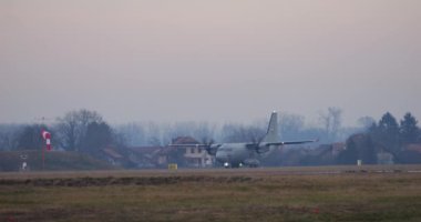 Cerklje ob Krki, Slovenya, 20 Aralık 2023: NATO askeri kargo uçağı Leonardo C-27J Spartan, kasvetli ve sisli bir kış gününün arka planına karşı kalkış için hazırlanıyor..