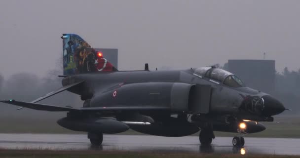 空軍F 4ファントムIi戦闘ジェットタクシーは 激しい雨の中で濡れた滑走路で トルコがNatoに参入した記念日を記念して塗装された尾 ランディングギアライトは水を反射します — ストック動画
