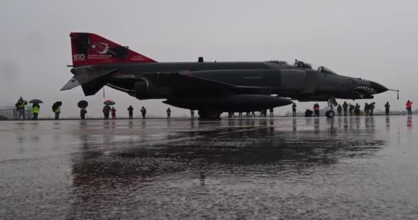 在大雨中停放的战斗机 从一个较低的角度来看 显示了喷气式飞机惊人的反光和被水淹的水面上的倾盆大雨 — 图库视频影像