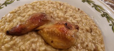 Kremalı risotto yatağında servis edilen lezzetli bir bıldırcın bacağına yakın plan.