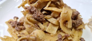 Geleneksel tagliatelle makarnasıyla karıştırılmış sağlıklı bir ragu sosu beyaz tabakta.