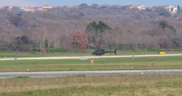 プーラクロアチア 2024年3月23日 敵の観測のためにロータートップの球形センサーを装備した黒い軍用ヘリコプターが緑の丘から離陸します クロアチア空軍のベルOh 58キオワ — ストック動画
