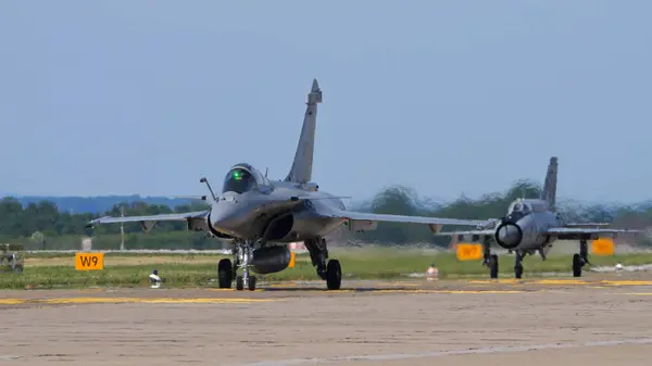 stock image Zagreb Croatia May 11, 2024: Dassault Rafale fighter jet taxiing on military airfield runway with a MikoyanGurevich MiG-21 in the background. Clear blue sky, ideal for showcasing air force technology