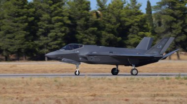 Atina 3 Eylül 2023: Arka planda ağaçlarla birlikte savaş uçağı pistte taksicilik yapıyor. Uzayı kopyala Lockheed Martin F-35 Lightning II Birleşik Devletler Hava Kuvvetleri.